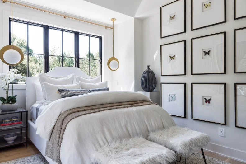 White bedroom with nine framed butterfly canvases and white bed.